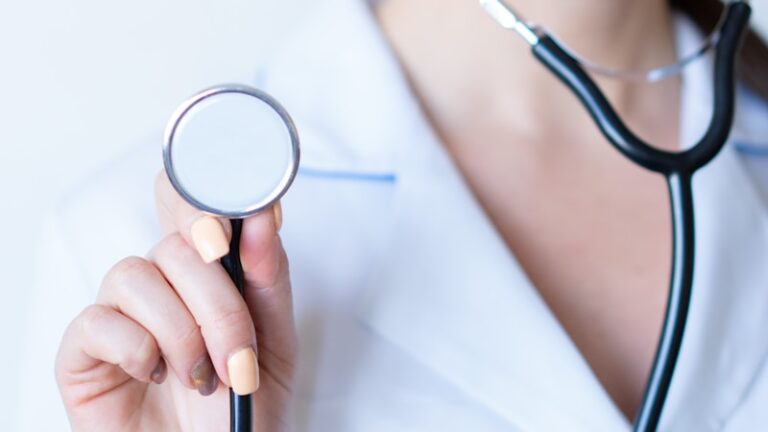 a woman in a white shirt holding a stethoscope